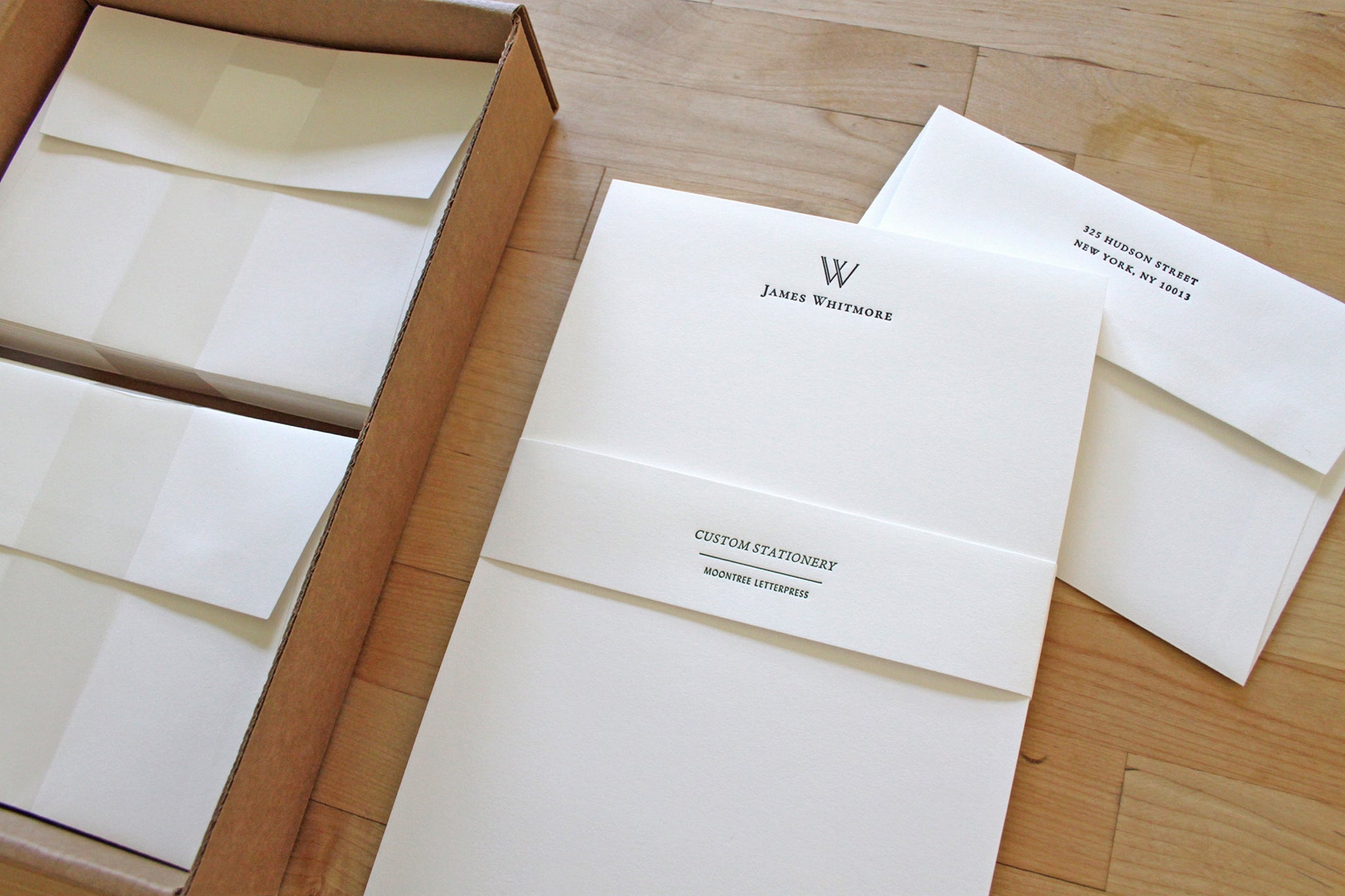 Personalized letterpress stationery with architectural initial, shown in an open box with matching return-address envelopes