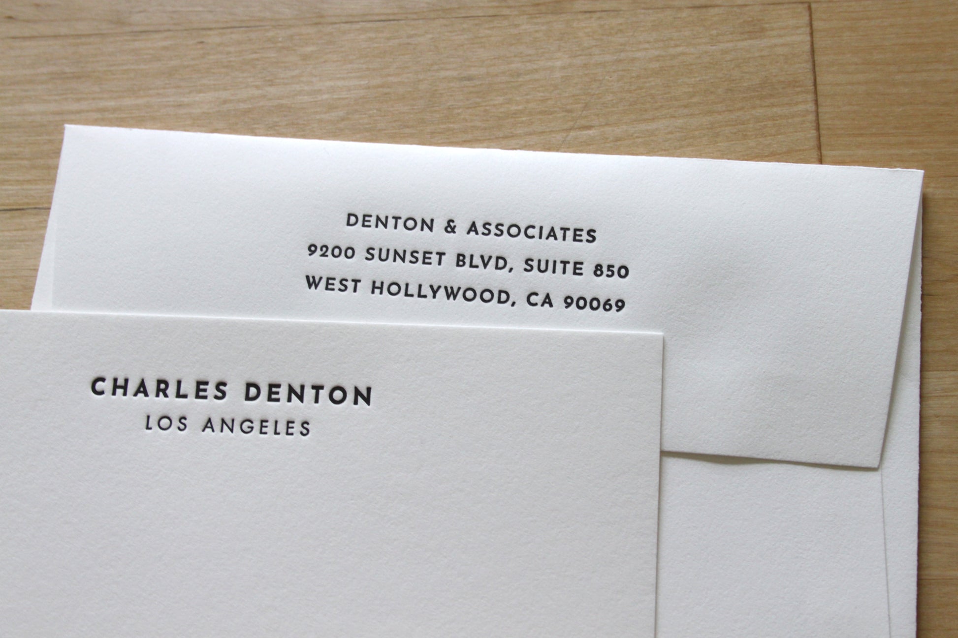 Personalized Bold Headline letterpress notecards fanned on wood surface, bold condensed name type with city, professional stationery for executives and attorneys