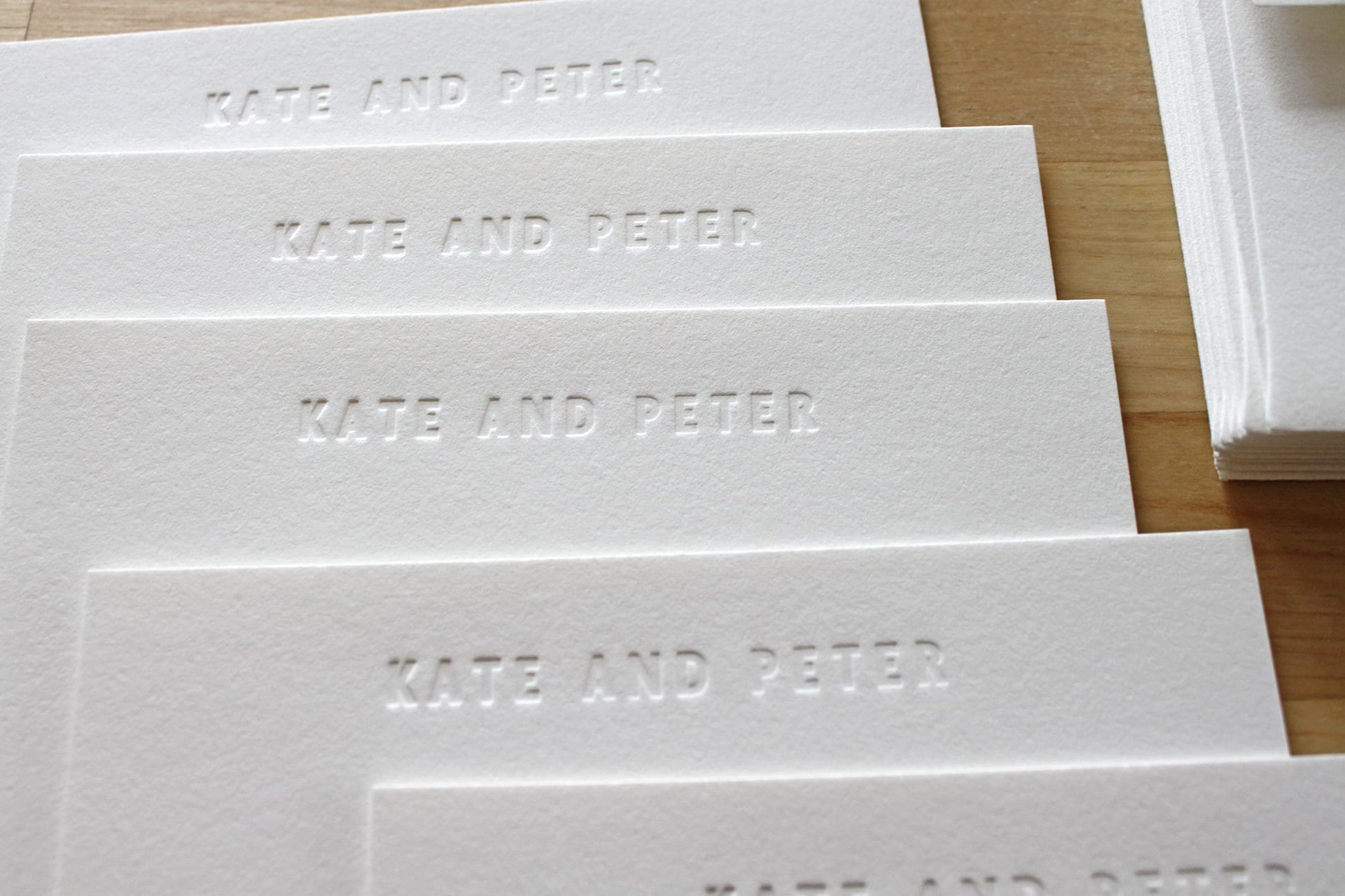 Stack of blind embossed bold type letterpress stationery showing name pressed into cotton paper