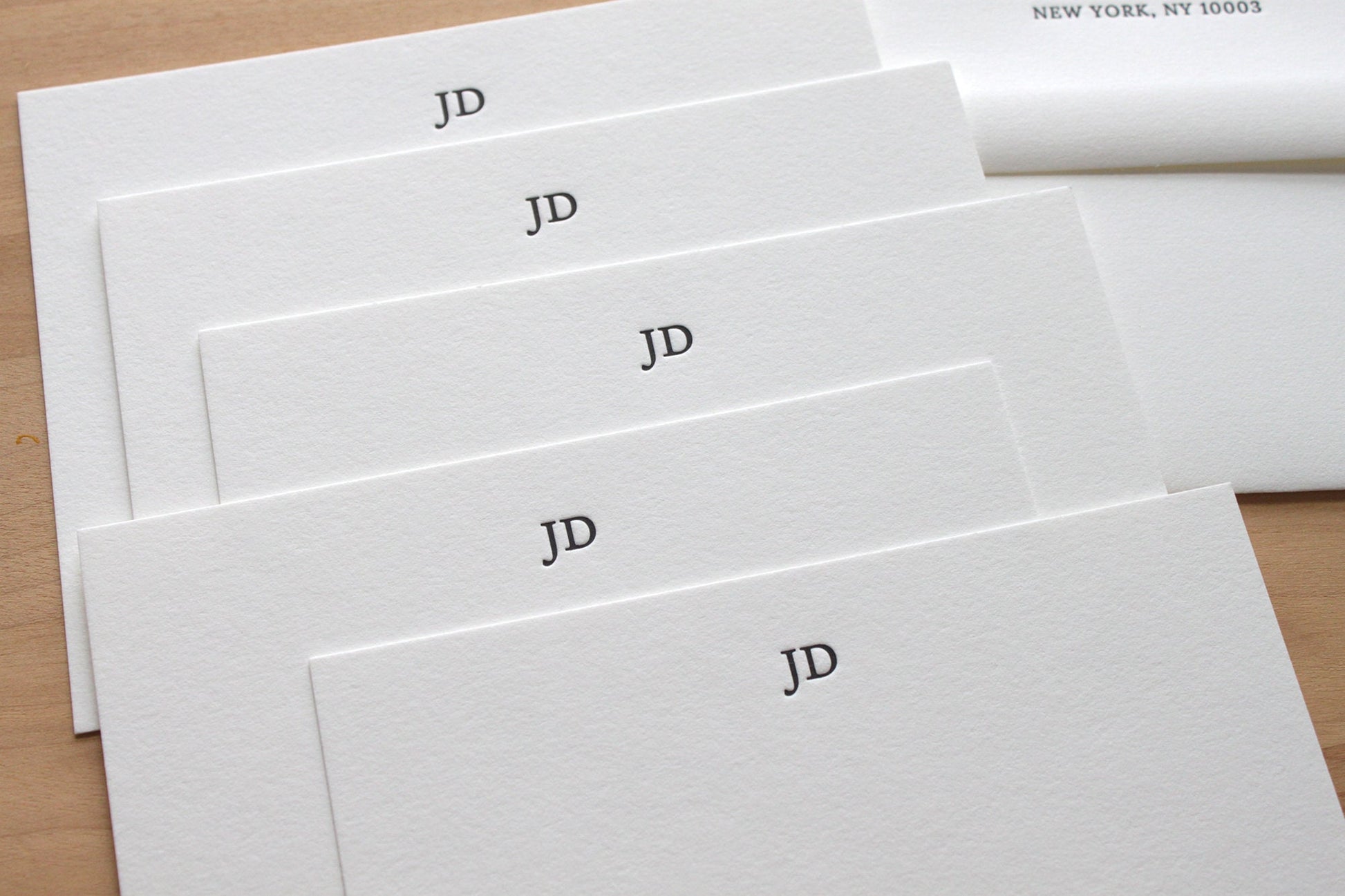 Stylish initials letterpress stationery in a stack with return addressed envelopes