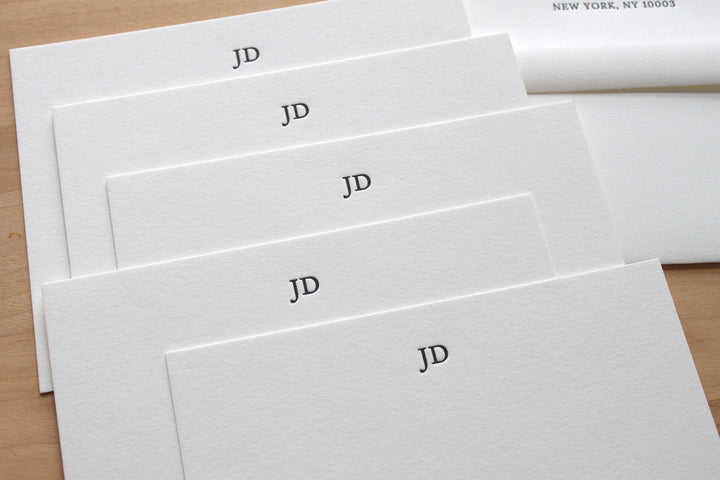 Stylish initials letterpress stationery in a stack with return addressed envelopes