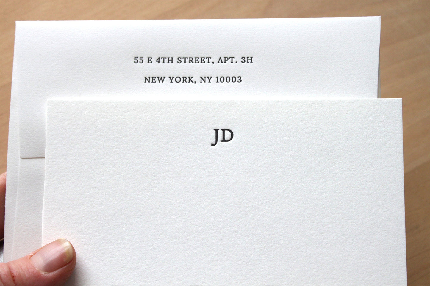 Hand holding personalized monogram letterpress notecard with JD initials and return address on cotton paper