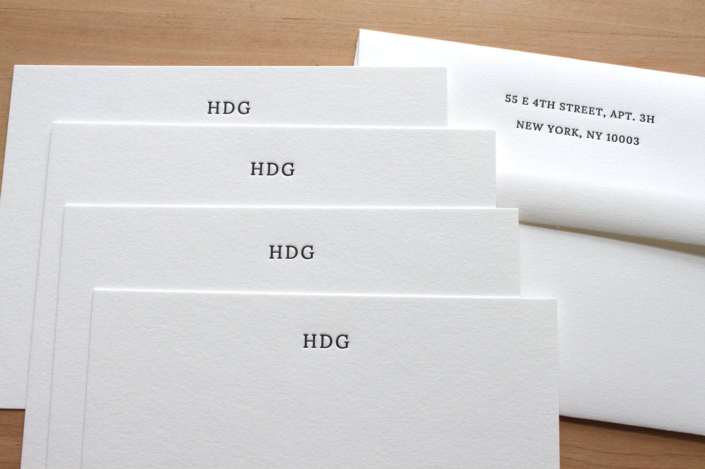 Stack of small initials letterpress notecards fanned showing discreet HDG monogramand return address envelopes